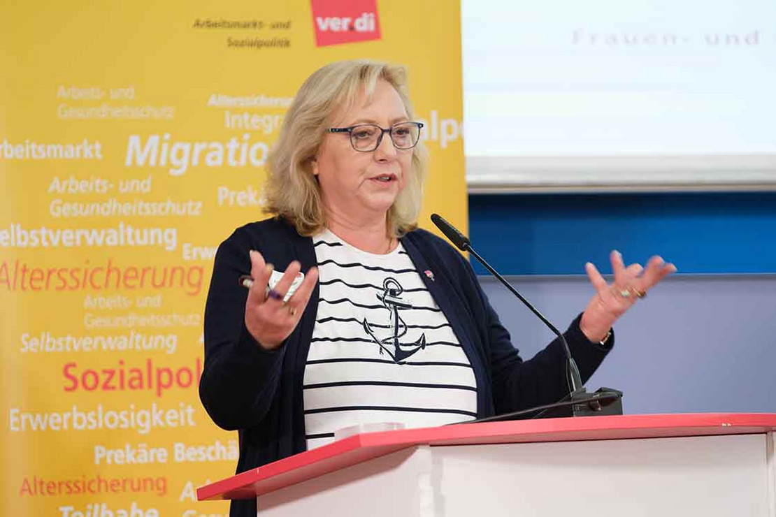 Frau am Pult spricht in ein Mikrofon.