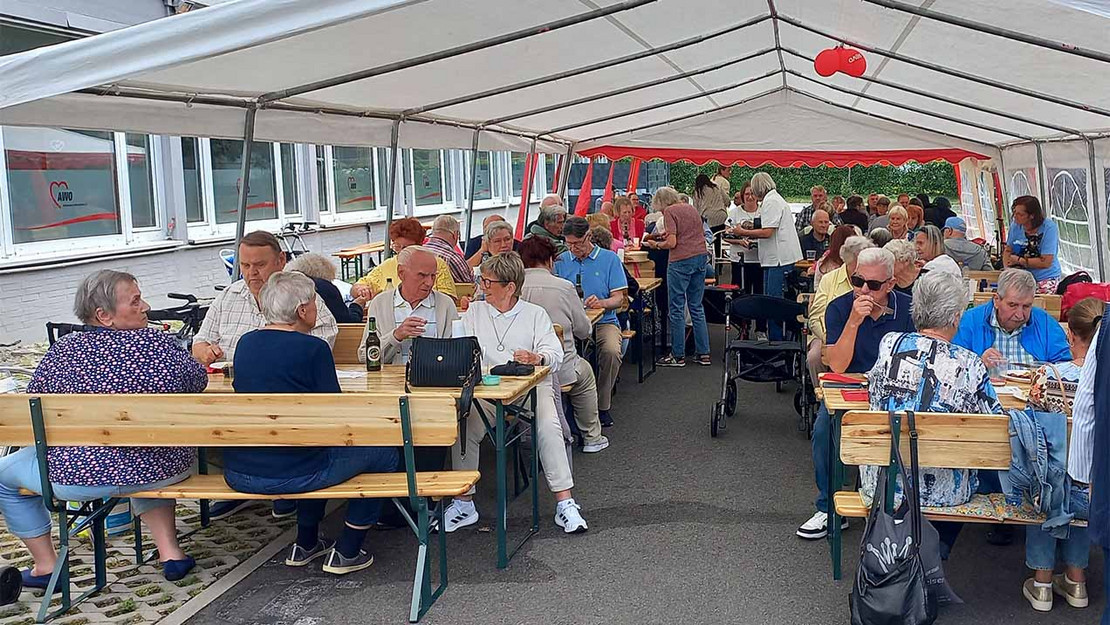 Vollbesetzte Bänke und Tische in einem Festzelt.