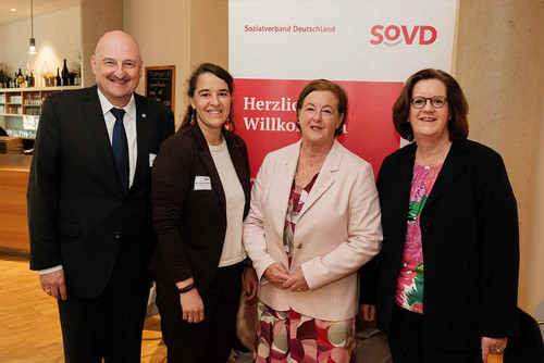 Vier Personen vor einem SoVD-Aufsteller. 