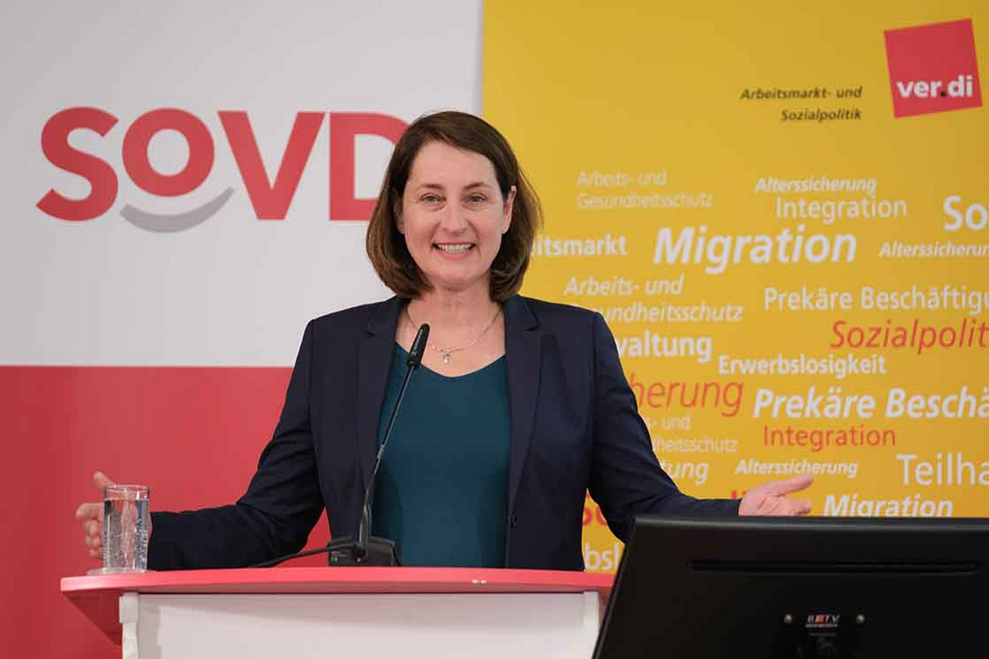 Frau spricht am Pult mit Mikrofon.