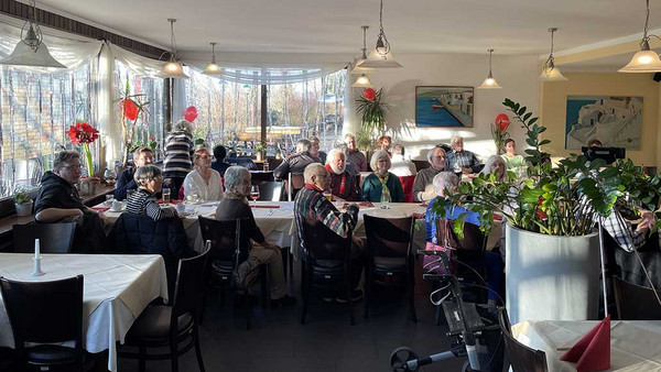 Menschen sitzen an Tischen im geschmückten Saal