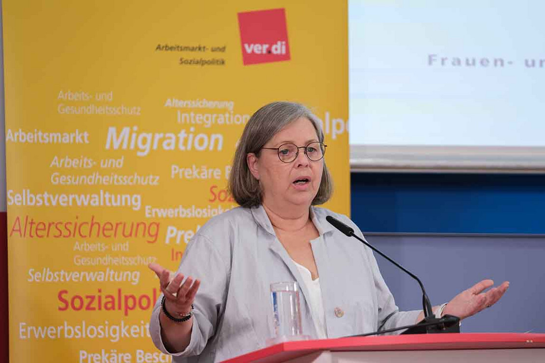 Frau spricht vor gelbem Aufsteller.