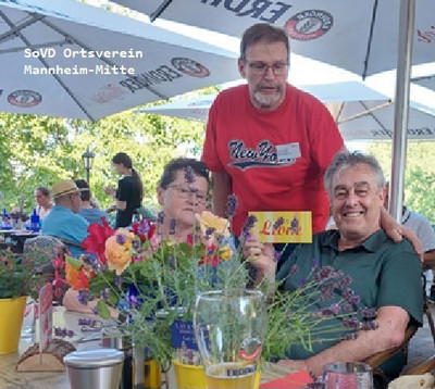 Drei Personen an einem Tisch im Biergarten.