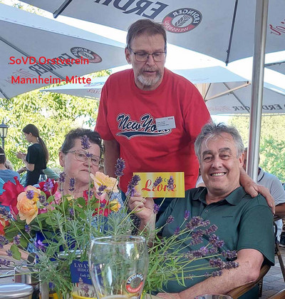 Drei Personen an einem Tisch im Biergarten.