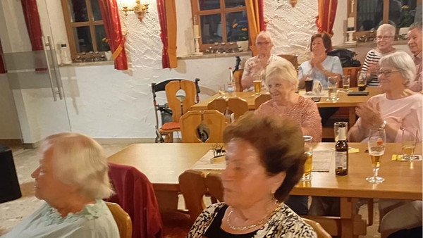 Menschen an Tischen hören jemandem zu.