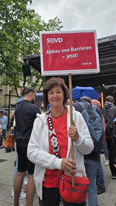 SoVD-Landesgeschäftsführerin Heike Sommerauer-Dörzapf mit Plakat auf der Demo in Stuttgart.