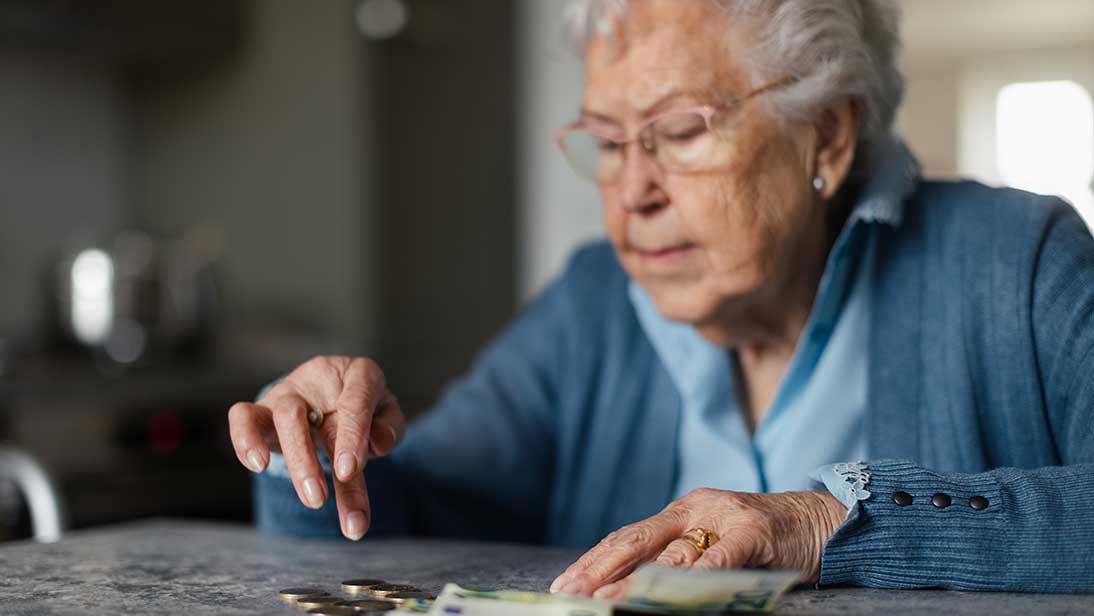Ältere Frau zählt Geld auf einem Tisch. 