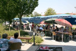 Sommerfest mit Besuchern an Tischen unter Sonnenschirmen